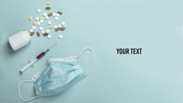 Coronavirus vaccine and treatment. Virus strain, syringe and pills, face mask on blue background. Medical concept. Copy space