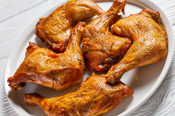 roast chicken legs on a white platter, top view