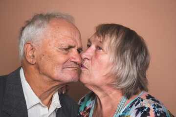 Portrait of adorable senior couple of pensioners in love; wife and husband kissing