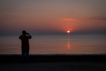 Fototapeta na wymiar a men on the beach is taking photo on the sunshine on the sea 