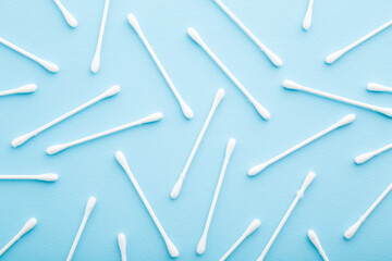 White sticks of cotton bud on light blue table background. Pastel color. Closeup. Top down view.