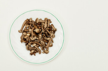 salted mushrooms in a white saucer on a sheet of paper