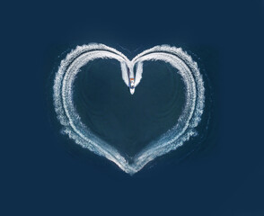 one boat form a shape of a heart on the ocean surface; aerial top down view