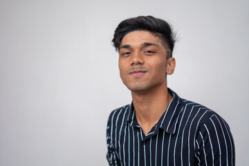 portrait of a cute asian boy with good grooming wearing a shirt look into the camera against white wall.