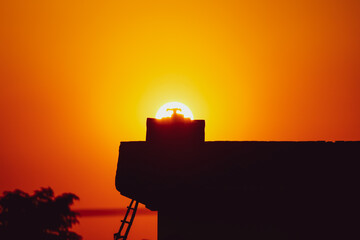 silhouette of a rooftop with a tank at sunset