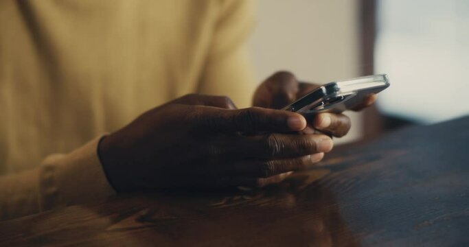 Crop black man text messaging on modern smartphone