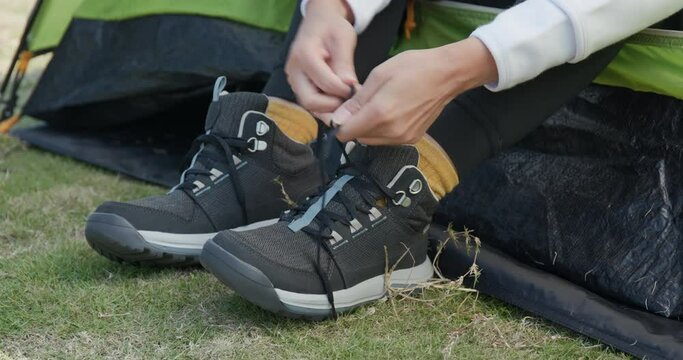 Woman tying her shoes after hiking at camping site