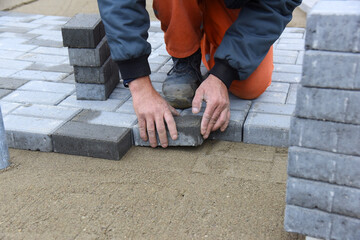 A worker lays concrete tiles on the sand, the planned construction of the road.
