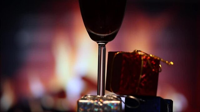 glass of red wine and gift boxes in front of the fireplace