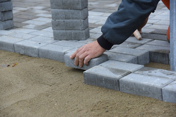 The builder settles the paving slabs in even rows, close-up.Construction of a road for pedestrians.