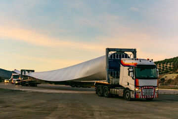 Fototapeta premium Special transport of blades for wind turbines, truck transporting a wind turbine blade that due to its large size requires a special adapted semi-trailer and accompanying vehicles (or galibos) for saf