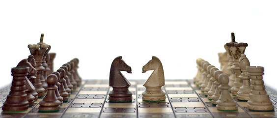 Chess faceoff of both knight horses on top of a chess board in front of a white background...