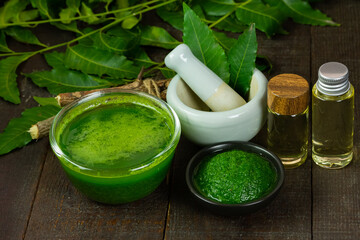 Neem leaf used as ayurvedic medicine with neem oil and stick on wooden background.