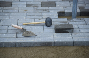 A close-up of a construction tool lying on a paved paving slab.