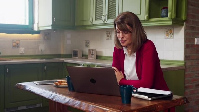 Senior woman typing on laptop at home