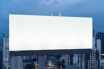 Fototapeta premium Blank white road billboard with KL cityscape background at night time. Street advertising poster, mock up, 3D rendering. Front view. The concept of marketing communication to promote or sell idea.