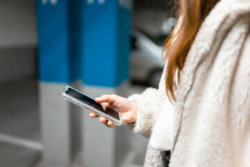 Woman hand with cell phone in hand in underground car parking