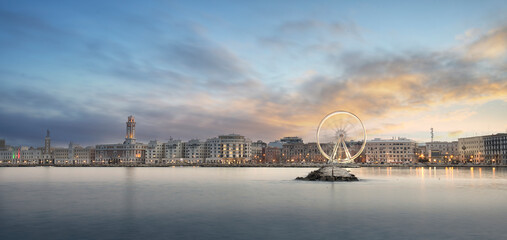 Panoramic sunset view of Illuminated giant Ferris wheel on the waterfront of Bari, region of...