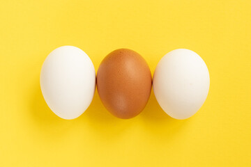 Close-up view of raw chicken eggs on yellow background.