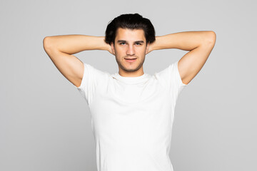 Happy young man holding hands behind head and looking up isolated on white background