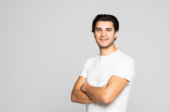 Portrait Of Smiling Handsome Man In White Tshirt Standing With Crossed Arms Isolated On White Background