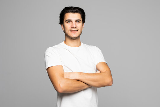 Portrait of smiling handsome man in white tshirt standing with crossed arms isolated on white background