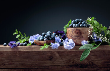 Summer still life with blueberries, colored sweet peas and meadow grasses on an old wooden table.