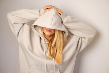 Young beautiful girl in a white hoodie posing. Warm oversized hoodie with an hood. Stylish trendy...