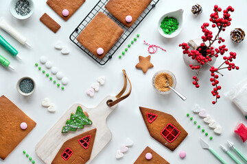 Making of gingerbread house, baked details arranged on white background. Xmas festive background. Flat lay arrangement. Creative handmade project for family holidays. Top view, creative festive food.