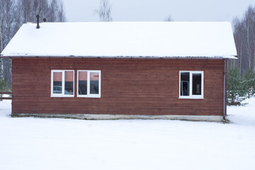 one-story wooden house stands in the snow