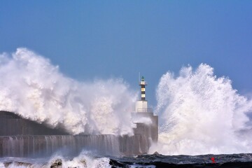Stormy wave over lighthouse of San Esteban de Pravia.