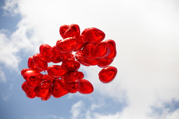 Red balloons with heart shape with sky and clouds in the background