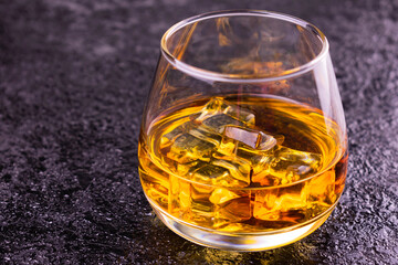 
Glass of cognac with ice on a black background.Copy space.