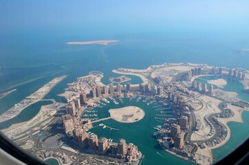 The Pearl-Qatar island in Doha through the airplane porthole, aerial view