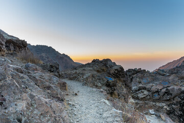 Obraz premium Barren mountain in Darband valley in dawn against colorful sky in the Tochal mountain with background of Tehran city in the morning. A popular recreational region for Tehran's residents