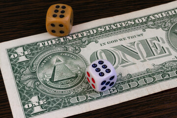 One dollar banknote and dice lying on the table.