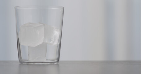 closeup ice cubes in tumbler glass on concrete countertop