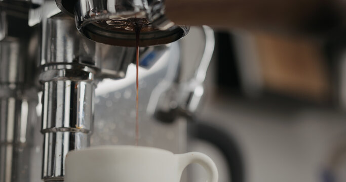 low angle shot of espresso extraction from naked portafilter into white cup