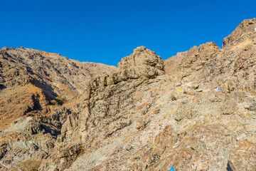 Fototapeta premium Barren mountain in Darband valley in autumn in the morning against blue sky in the Tochal mountain. A popular recreational region for Tehran's residents