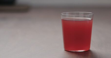 pink fizzy drink in a tumbler glass from walnut table