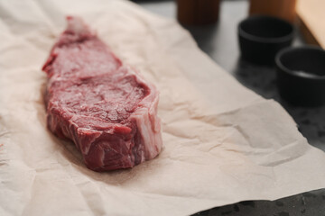 Raw new york sirloin steak on parchment paper warming up before cooking