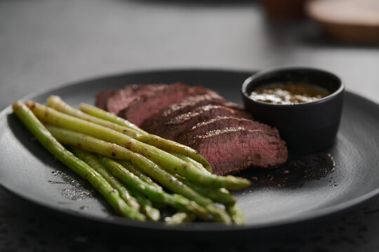 New york steak with asparagus on black plate with pesto sauce