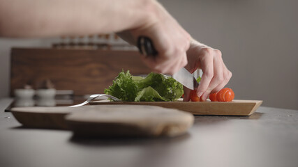 Man slicing cherry tomatoes for sandwich on kitchen countertop