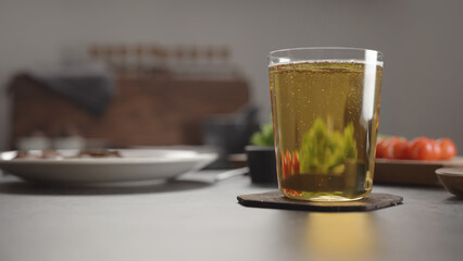 apple cider in a tumbler glass on concrete countertop with window on background