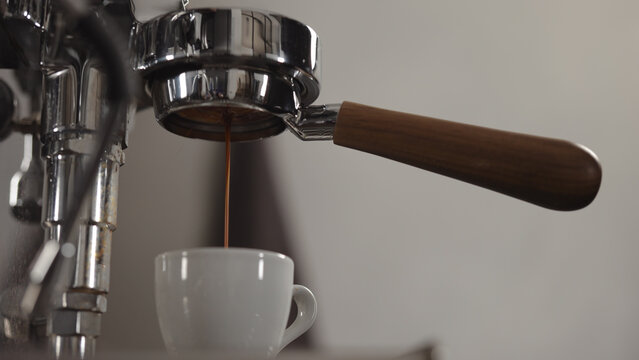 low angle shot of espresso extraction from naked portafilter into white cup