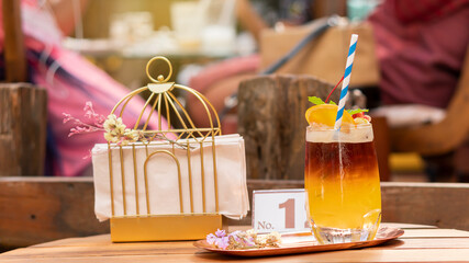 Glass of lemon tea, drinks on the table with a paper basket placed next to it.