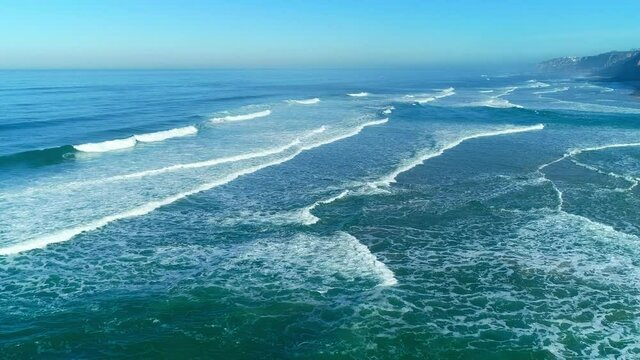 An aerial shot of sea waves surging against the seacoast consecutively at the Victory Walls Beach in south-west Portugal