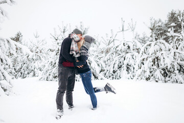 Fototapeta na wymiar A loving couple kissing in a snowy beautiful forest in winter
