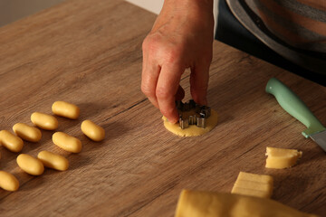 A closeup of a female hand using a cookie cutter and preparing cookies for a Christmas party