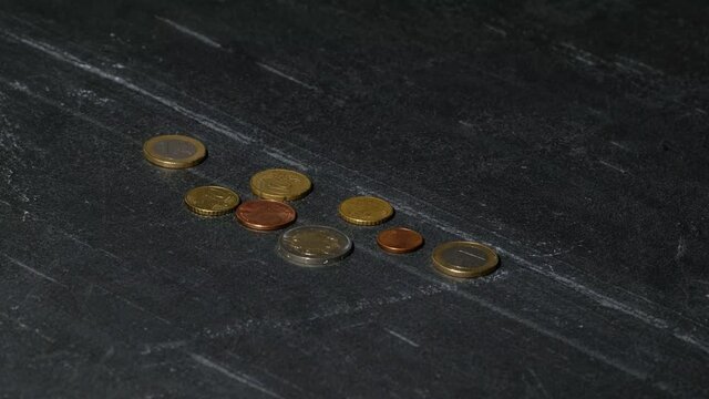 A few euro coins are lit up to a point and then fade easily on a black background. The economy was recovering until the second wave of the pandemic corona virus. Covid19 hits the economy. Stay safe.
